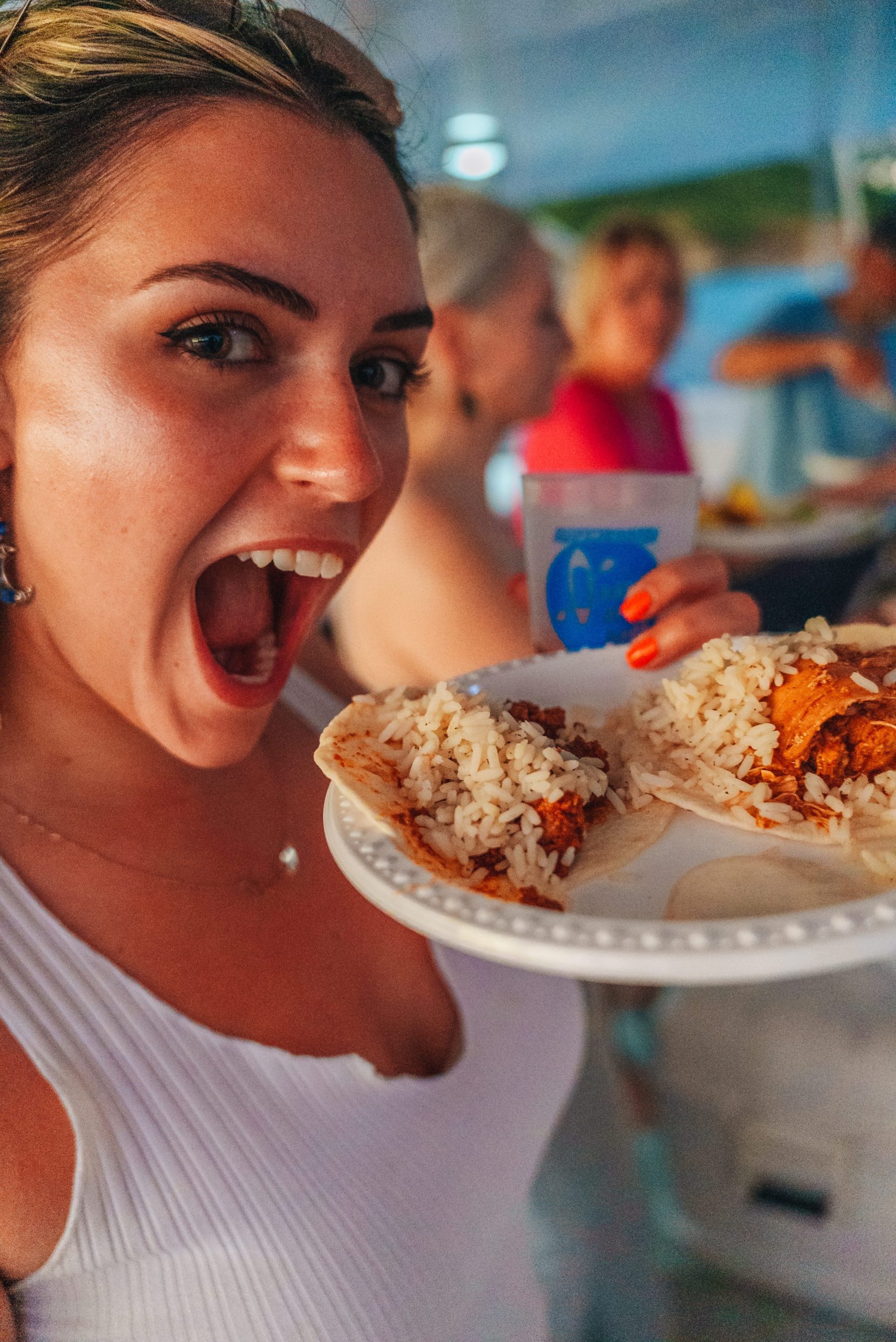 Person holding a plate with tacos, smiling widely.