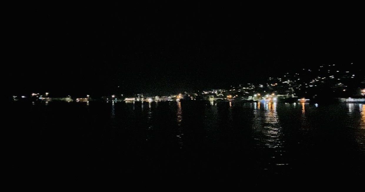 Night view of a city waterfront with scattered lights reflecting on the water.