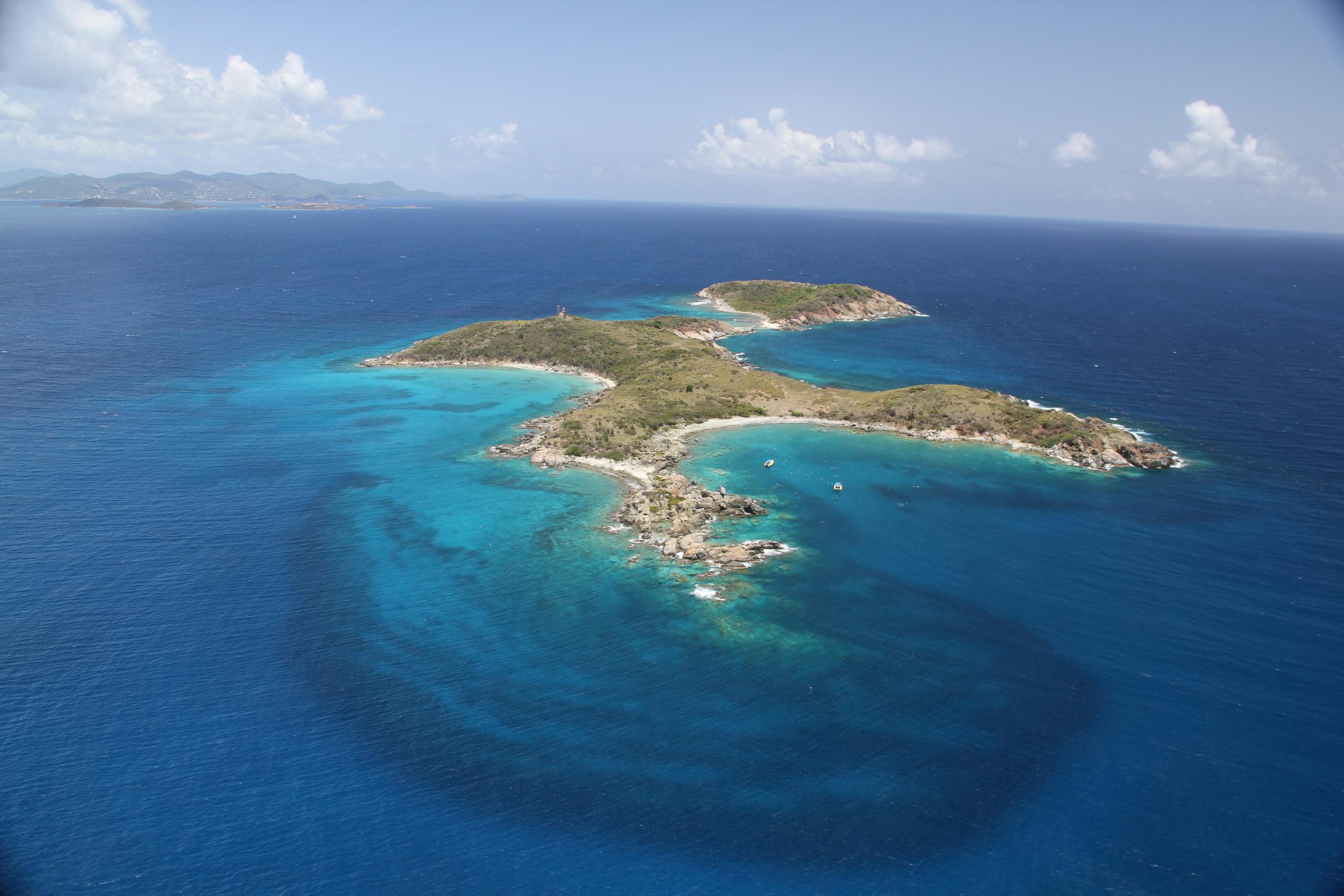 Aerial view of a small island with rocky coasts and surrounding blue ocean.