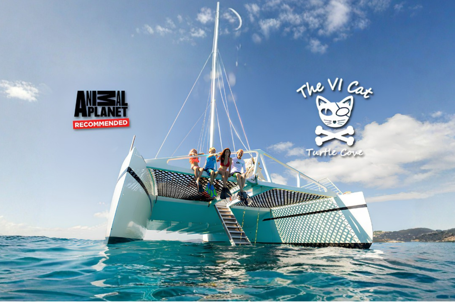 People on catamaran in clear blue sea with logos on sail.