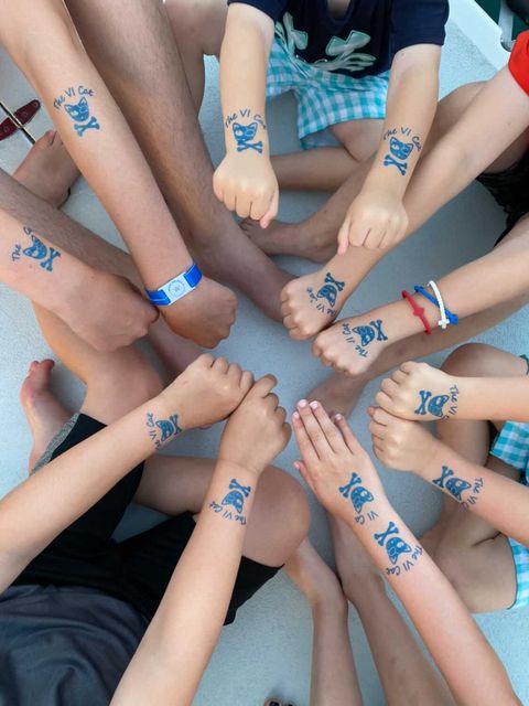 Group of hands with matching temporary fish tattoos.
